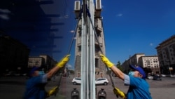 Женщина в защитной маске моет окно магазина. Москва, 28 мая 2020 года.