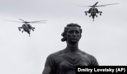 Military helicopters fly over a statue of the Mother Motherland at the Piskaryovskoye Memorial Cemetery, where more than half a million Leningrad Siege victims were buried during World War II.