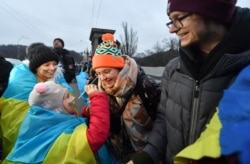 A girl paints the face of a woman with the colors of Ukraine's national flag as people form a human chain on a bridge across the Dnipro River in Kyiv, to mark the country's Day of Unity on January 22.