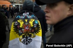 Putyin után hanyatlás jöhet, de kik lépnek a helyébe? Orosz nacionalista tüntető a birodalmi, fekete-sárga-fehér trikolórral az orosz egység napján, 2019. november 4-én