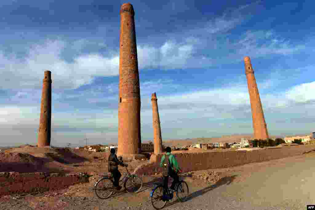 Afghan youths ride their bicycles past the historic minarets in Herat. (AFP/Aref Karimi)