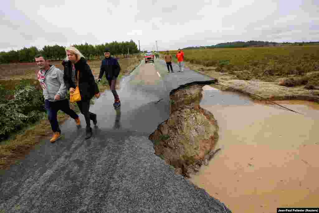 People walk on a road that was partially washed away after flash floods hit the southwestern Aude district of France. Several months' worth of rain fell in just a few hours. (Reuters/Jean-Paul Pelissier)