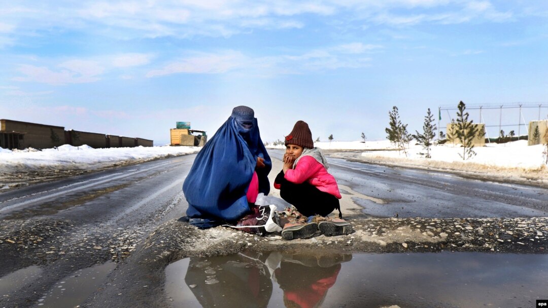 A burqa-clad woman and a girl beg on the outskirts of Kabul. (file photo)