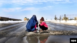 A burqa-clad woman and a girl beg on the outskirts of Kabul. (file photo)