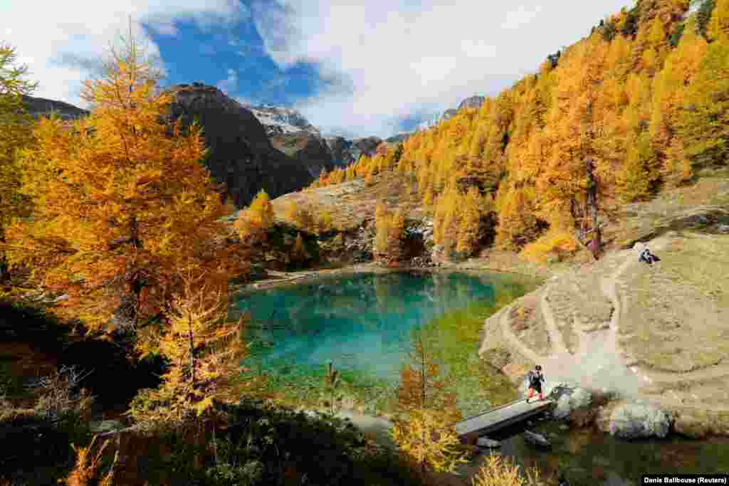 Alpinistët shijojnë një ditë të ngrohtë vjeshte në Lac Bleu pranë Arolla në Val d'Herens, Zvicër. 