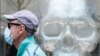 A man wearing a protective face mask, used as a preventive measure against the coronavirus disease (COVID-19), walks past a dummy skull placed in a shop window in central Kyiv, Ukraine July 13, 2020. REUTERS/Gleb Garanich