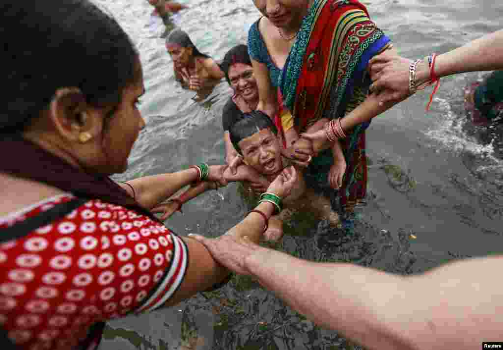A boy cries as he is dipped by his relatives in the Godavari River during Kumbh Mela, or the Pitcher Festival, in Nashik, India. Hundreds of thousands of Hindus took part in the religious gathering, which is held every 12 years in different Indian cities. (Reuters/Danish Siddiqui)