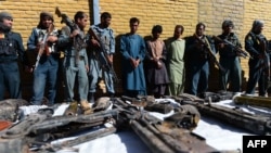 Afghan policemen stand with Taliban fighters behind a table with their seized weapons on September 29.