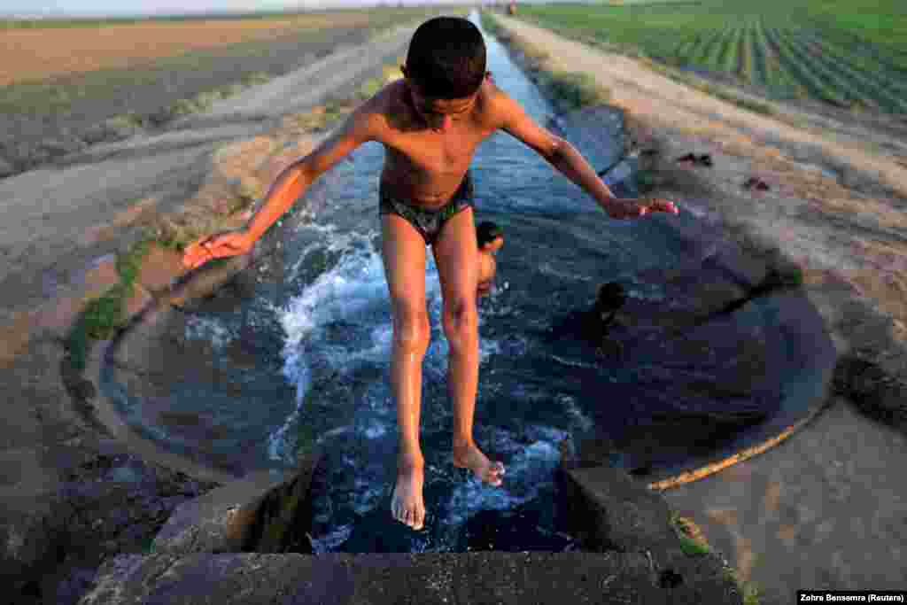 A boy cools off in an irrigation canal on the outskirts of Raqqa, Syria. (Reuters/Zohra Bensemra)