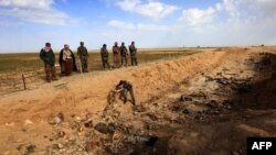 Iraq -- Members of the Yazidi minority search for clues that might lead them to missing relatives in the remains of people killed by the IS jihadist group, a day after Kurdish forces discovered a mass grave near the Iraqi village of Sinuni, 3Feb2015.