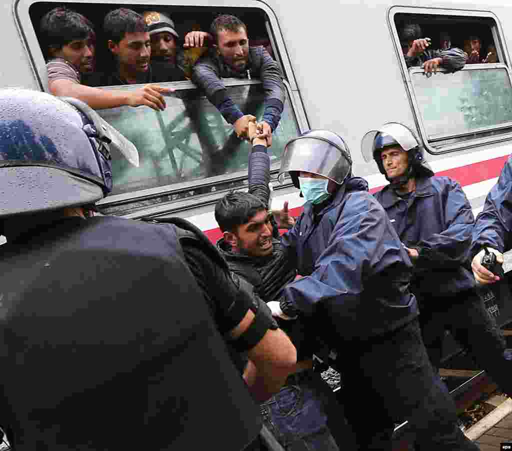 Croatian police push back a migrant who had tried to climb through the window to get aboard a train bound for Hungary and Austria at a railway station at the Croatian-Serbian border, near Tovarnik, Croatia. (epa/Antonio Bat)