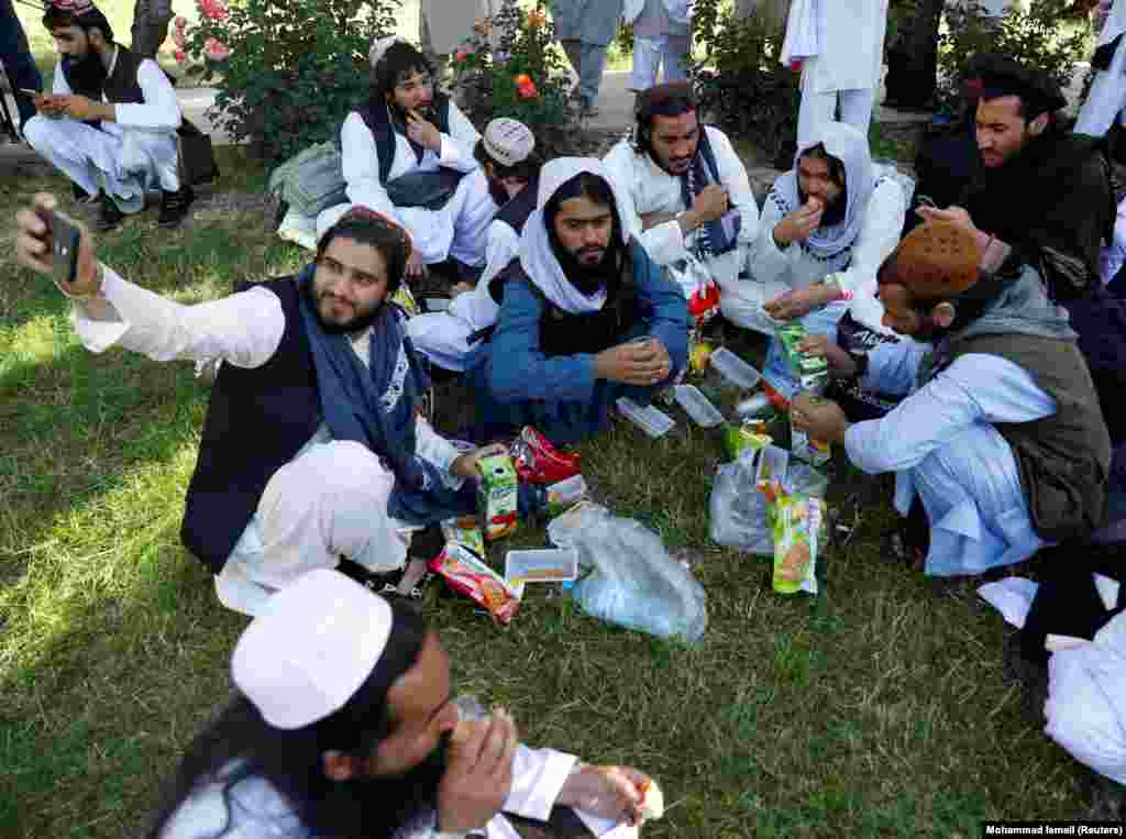 A newly freed Taliban prisoner takes a selfie as others have juice and biscuits outside Pul-e-Charkhi prison near Kabul on May 26. Former detainees were given new clothes and cash.