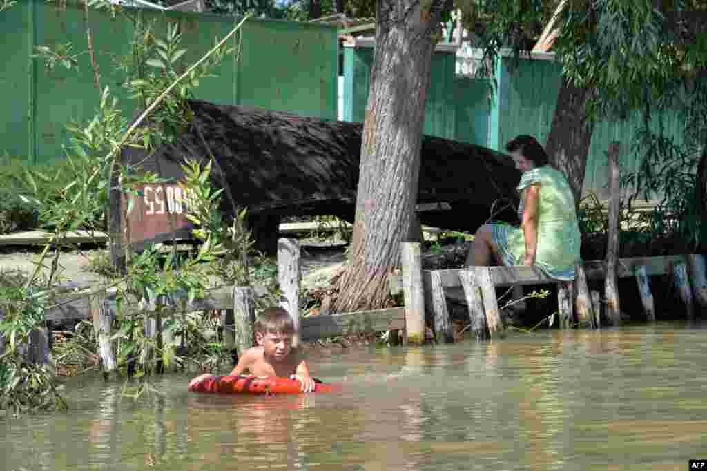 A boy swims in a channel in front of his family&#39;s house.