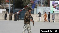 An Afghan policeman walks near the site of an explosion in Kabul on March 21