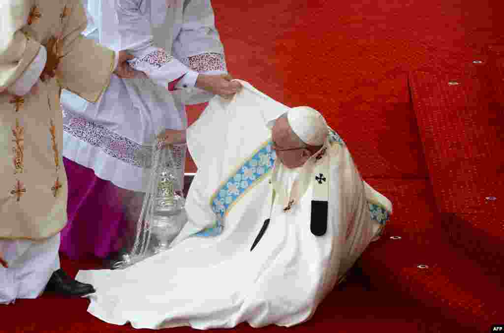 Pope Francis is helped onto his feet after falling on steps during a mass at the Jasna Gora Monastery in Czestochowa, Poland, on July 28. (AFP/Filippo Monteforte)