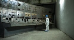 Čovjek gleda kontrolnu tablu obloženu gljivama na černobilskoj nuklearki.