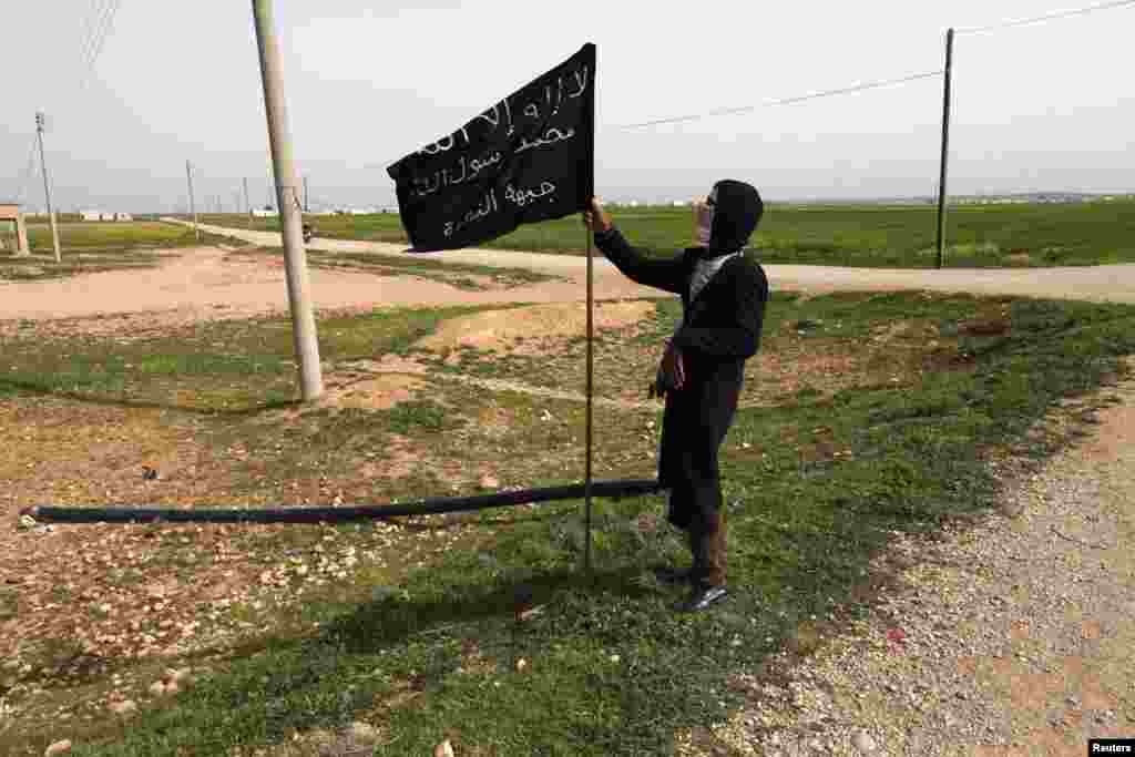 Боевик радикальной группировки &quot;Джабхат ан-Нусра&quot; с ее флагом в провинции Ракка, 12 марта 2013 года &nbsp;