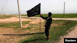 Një kryengritës e mbanë një flamur islamik në provincën Raqqa në Siri