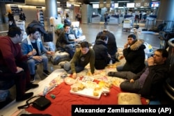 Tajiks eat on the floor while waiting for a plane to return them to their home country at the Vnukovo International Airport, near Moscow.