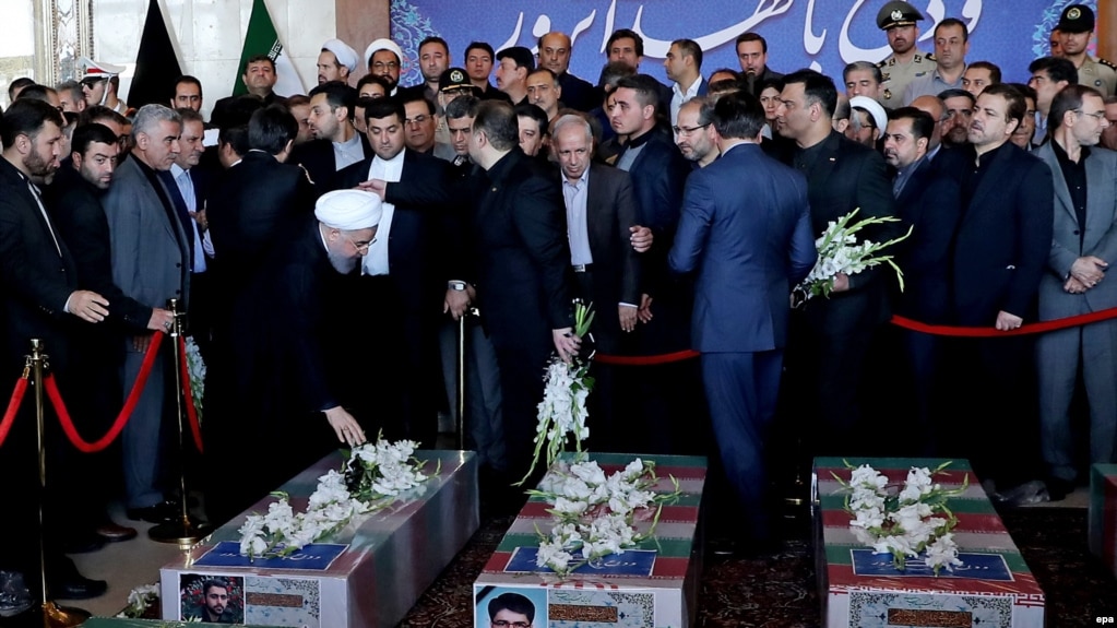 Iranian President Hassan Rohani (left) prays near the coffins of victims who died in a terror attack at the Iranian parliament in Tehran.