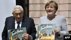 Fostul secretar de stat american din epoca Brejnev, Henry Kissinger și fostul cancelar german, Angela Merkel, în iunie 2017, la Institutul George Marshall de la Berlin în iunie 2017. Ambii au avut politici de compromis față de URSS/Rusia, respectiv China.