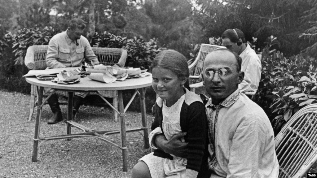 A photograph dated 1935 showing Soviet leader Joseph Stalin (background left) at his dacha with his chief security and police, Lavrenty Beria (right), who has Stalin's daughter Svetlana on his knee.