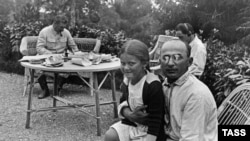 A photograph dated 1935 showing Soviet leader Joseph Stalin (background left) at his dacha with his chief of security and police, Lavrenty Beria (right), who has Stalin's daughter Svetlana on his knee. 