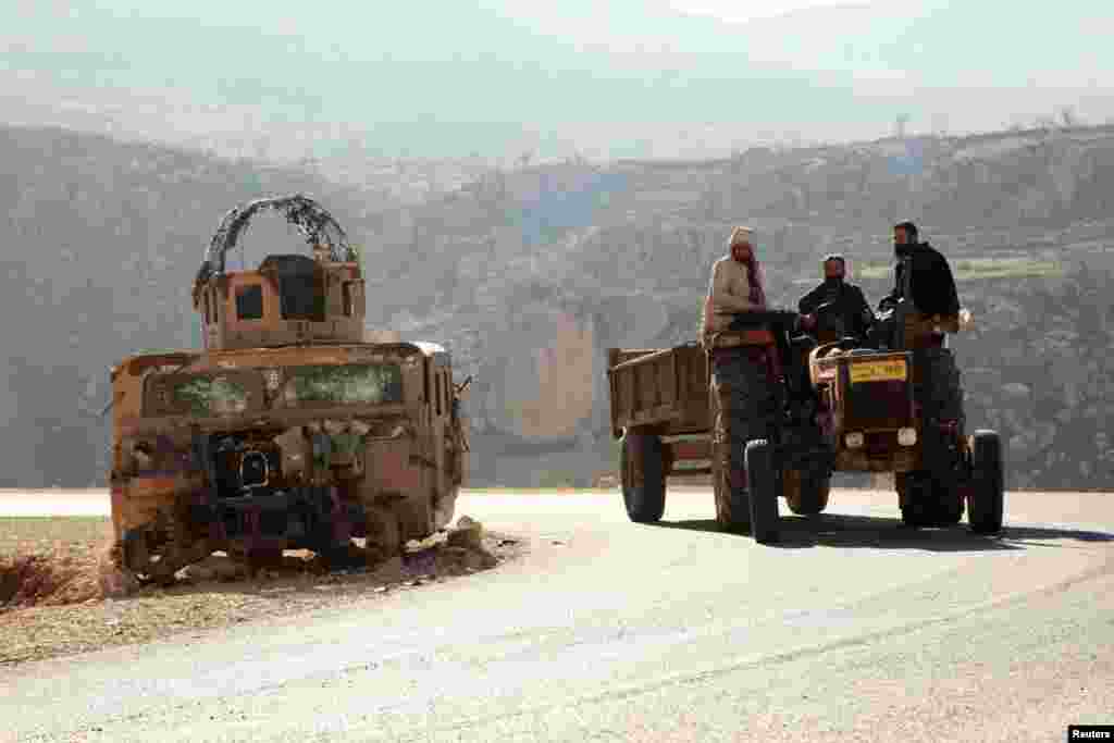 People from the minority Yazidi sect pass a destroyed military vehicle belonging to Islamic State militants at Mount Sinjar, in the town of Sinjar, Iraq. (Reuters/Ari Jalal)