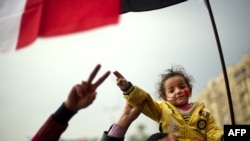 An Egyptian girl sits on the shoulders of her father during ongoing pro-reform demonstrations on Cairo's Tahrir Square.