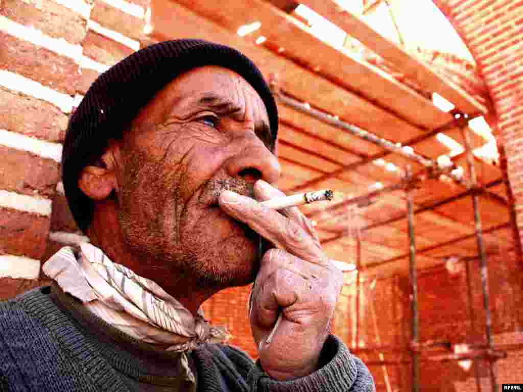 A worker takes a smoke break while laying asphalt in Ardabil, Iran. - Photo by RFE/RL