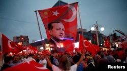 A supporter holds a flag depicting Turkish President Tayyip Erdogan during a pro-government demonstration in Ankara, Turkey on July 20.