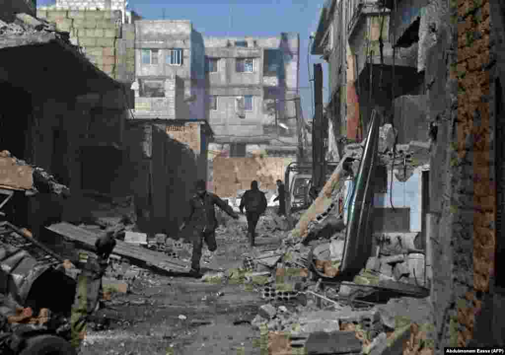 Syrian men run through an alley in the rebel-controlled town of Mesraba outside of Damascus on November 27. (AFP/Abdulmonam Eassa)