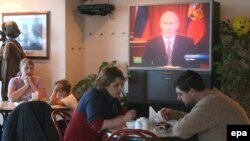 Russians listen to an address by then-President Vladimir Putin. Growing wealth in Russia has come at the expense of civil society and certain freedoms.