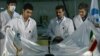 Iranian President Mahmud Ahmadinejad (center) looks on as scientists unveil a fuel rod at the Tehran Research Reactor.