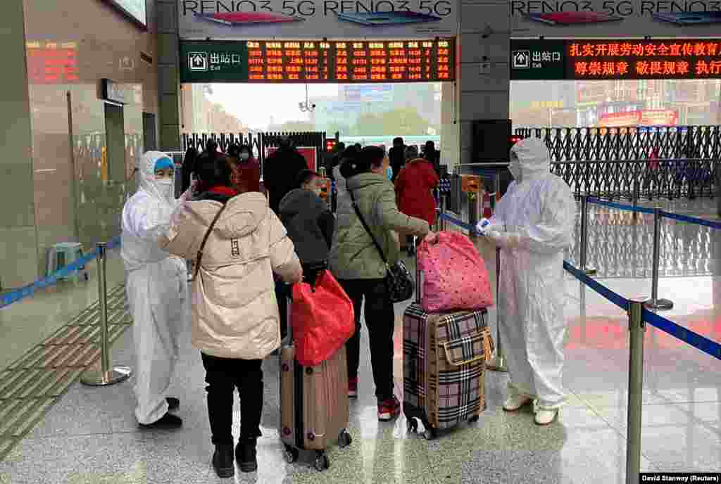 Медицинские сотрудники проверяют температуру у пассажиров, прибывших на Северный железнодорожный вокзал соседнего с Уханем города Сяньнин, 24 января 2020 года