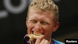 Александр Винокуров алтын медалін тістеп, олимпиаданың жеңіс тұғырында тұр. Ұлыбритания, Лондон, 28 шілде 2012 жыл.