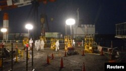 Работники в защитных костюмах на АЭС "Фукусима-1"