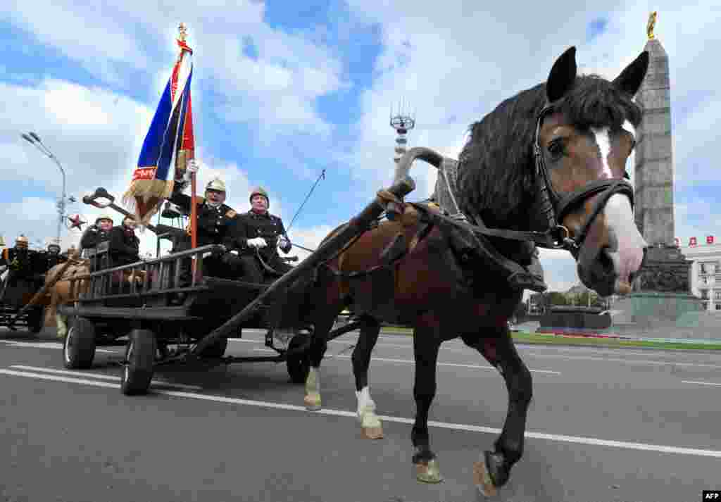 Belarusian firefighters ride on a horse-drawn carriage along the main avenue of Minsk to celebrate the160th anniversary of the state's fire service (AFP/Viktor Drachev)