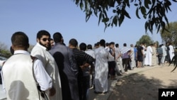 Libyans wait in line to view the body of ousted Libyan leader Muammar Qaddafi inside a cold-storage room in the outskirts of Misrata on October 21.