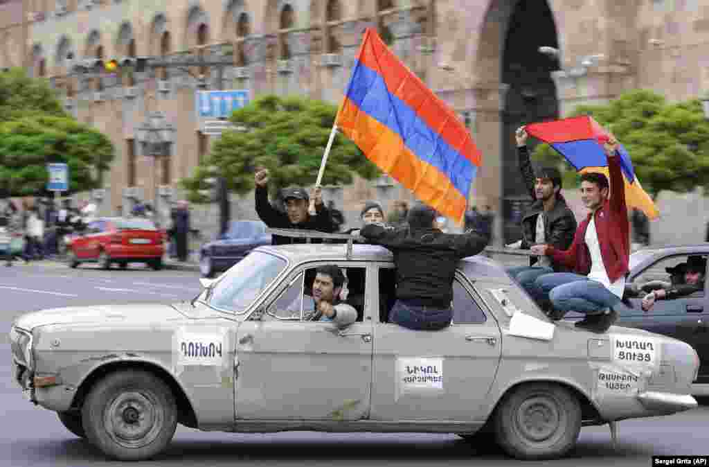 Antigovernment protesters hold Armenian national flags as they drive by Republic Square in Yerevan. (AP/Sergei Grits)