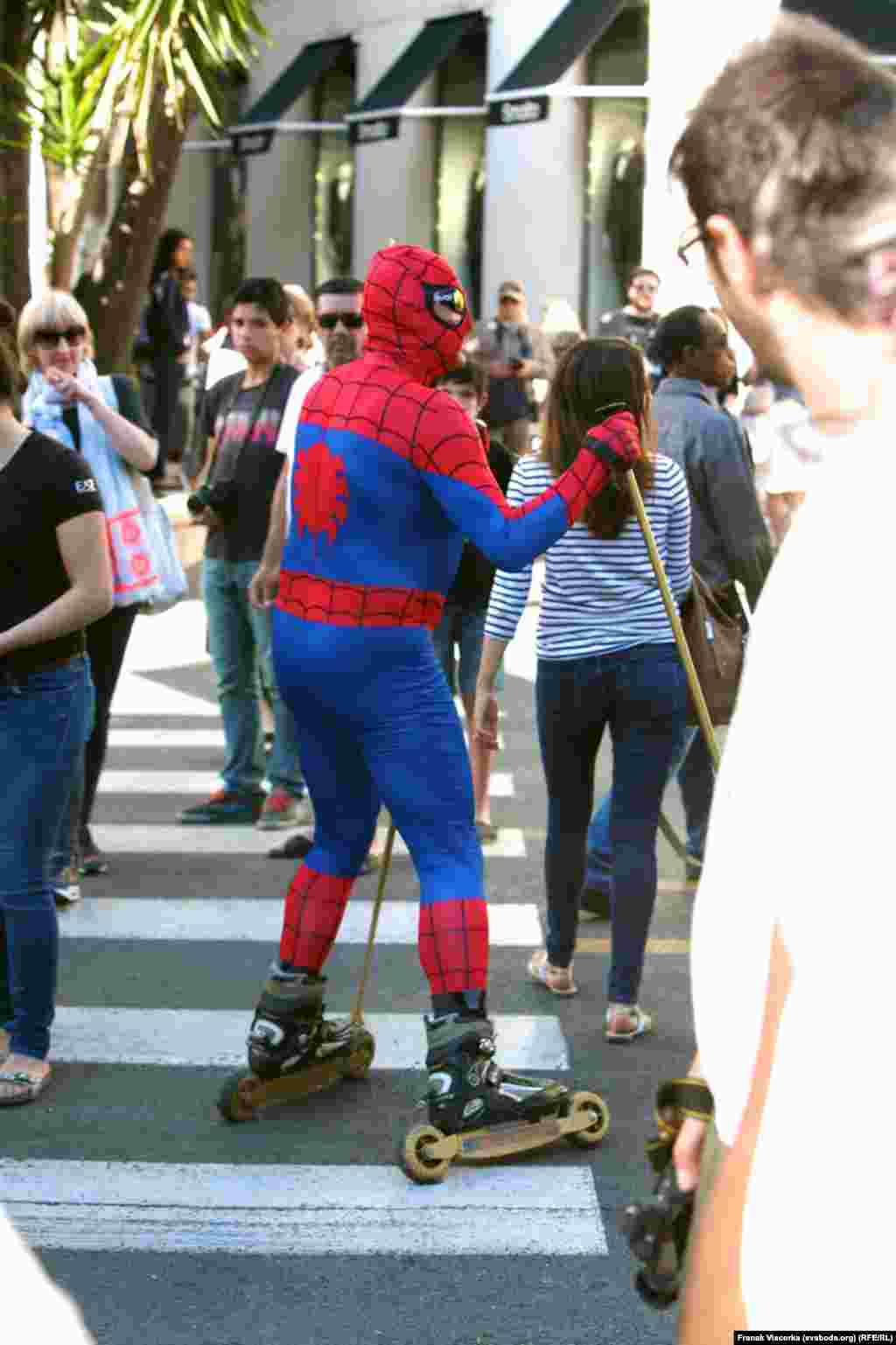 A man in a Spiderman costume skates through the streets of Cannes.