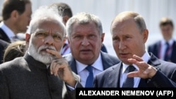 Russia's Vladimir Putin (right) speaks with India's Narendra Modi during a visit to the Zvezda shipyard, as Rosneft chief Igor Sechin (center) looks on, outside Vladivostok on September 4.