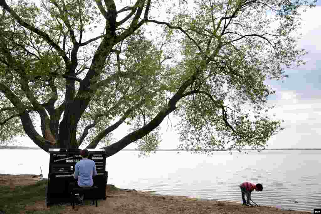 Музыкант грае на фартэпіяна на беразе возера на ўскрайку Менску.