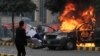 A lawyer throws a trash can toward police near a vehicle set on fire outside the Punjab Institute of Cardiology (PIC) in Lahore on December 11.