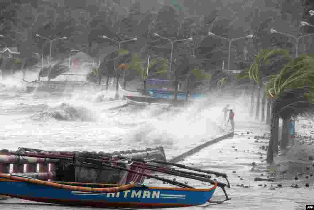 Philippines -- A resident (R) walks past high waves pounding the sea wall amidst strong winds as Typhoon Haiyan hit the city of Legaspi, Albay province, south of Manila on November 8, 2013. 