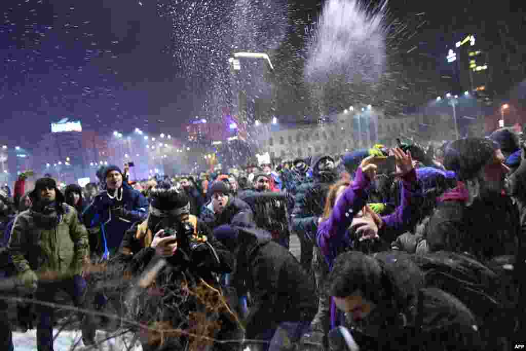 People throw snow toward police as they demonstrate in front of the Romanian government headquarters in Bucharest against controversial decrees to pardon corrupt politicians and decriminalize other offenses. (AFP/Daniel Mihaeilescu)