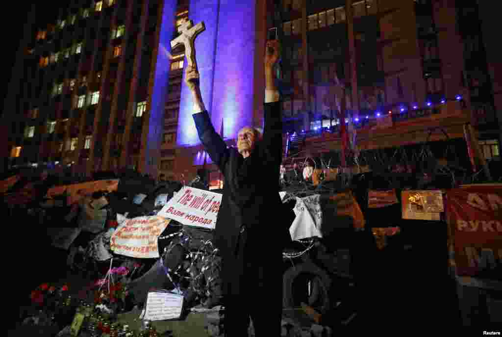 A man holds a cross and a telephone as he stands near a barricade erected by pro-Russian activists during a rally to mark and celebrate the announcement of the results of the referendum on the status of Donetsk region in Donetsk on May 12. (Reuters/Maksim Zmeyev)