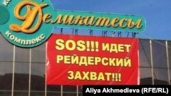 Баннер «SOS – идет рейдерский захват» висит на здании ресторана "Деликатесы" в Талдыкоргане.
