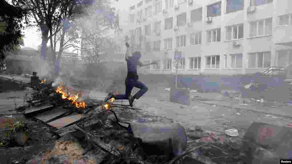 Maszkos tüntető égő barikádok mellett Mariupol központjában 2014. május 9-én. Május elejére szórványos lövöldözés kezdődött. A városközpontban felbomlott a rend, és bizonytalanná vált a helyi rendfenntartók lojalitása