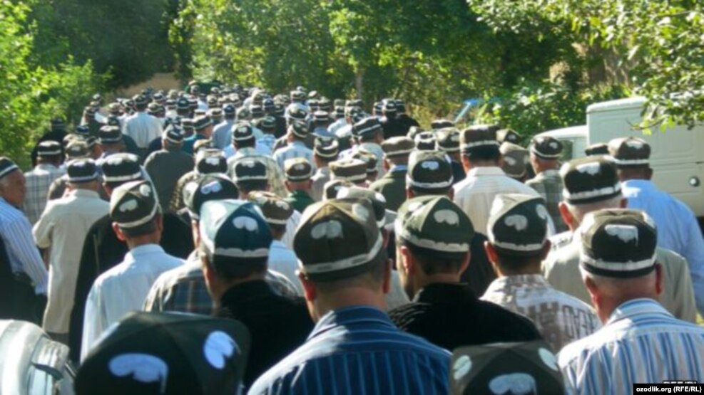 Мужчины в национальной тюбетейке, участвующие в похоронной процессии.